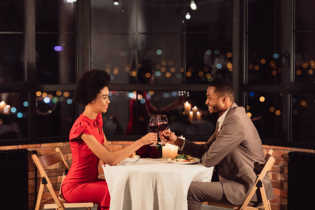 couples clignotant des verres buvant le vin célébrant la saint-valentin dans le restaurant - anniversary couple rose black photos et images de collection