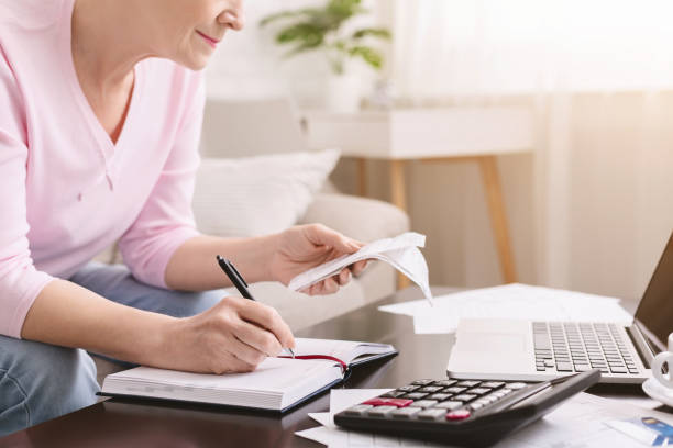 Senior lady counting bills and making notes at home Financial literacy. Senior lady counting bills and making notes at home, empty space financial literacy stock pictures, royalty-free photos & images