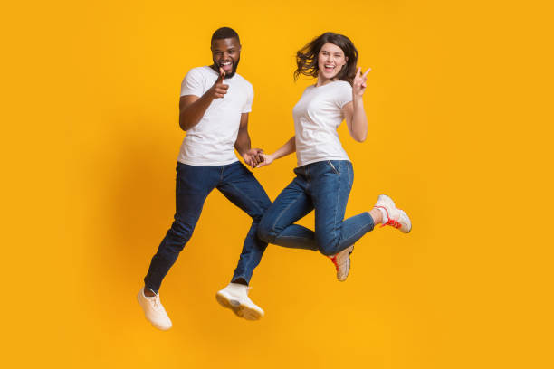 istock Playful multiracial couple jumping in air, having fun together 1201187366