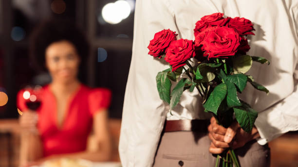 레스토랑에서 girfriend와 데이트를 갖는 장미를 들고 인식 할 수없는 남자 - anniversary couple rose black 뉴스 사진 이미지