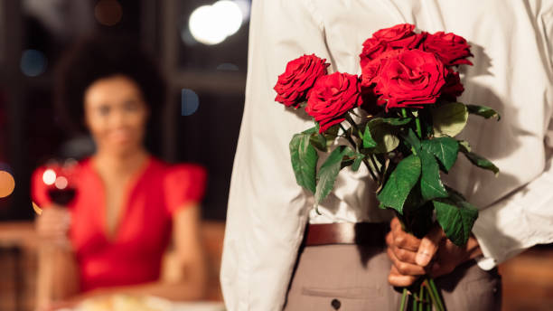 istock Unrecognizable Man Holding Roses Having Date With Girfriend In Restaurant 1201187861
