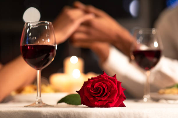 테이블에 누워 장미, 레스토랑에서 손을 잡고 사랑하는 커플 - anniversary couple rose black 뉴스 사진 이미지