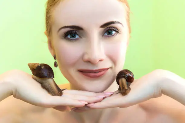 The cleansing facial at the beautician by snails Achatina. The girl at the beautician does Facials and skin rejuvenation of the face snails Achatina