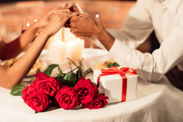 istock Couple Holding Hands, Valentine's Gift And Roses Lying On Table 1201188548
