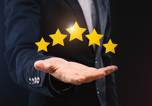 Best Business Services. Unrecognizable Businessman Holding Five Stars Icons On Open Hand, Demonstrating Rating Of His Company, Dark Background