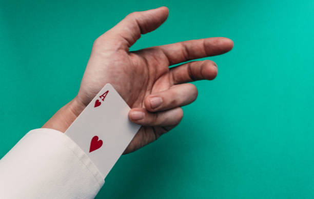 Man pulling an ace out of his sleeve by doing a trick in front of a poker table Man pulling an ace out of his sleeve by doing a trick in front of a poker table ace photos stock pictures, royalty-free photos & images