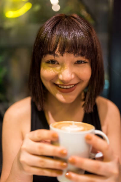 istock Beautiful young girl drinks coffee at cafe 1201189655