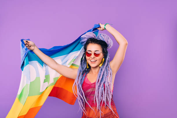 rainbow flag in the hands of a hipster woman. world peace. on a purple background - gay pride flag fotos imagens e fotografias de stock