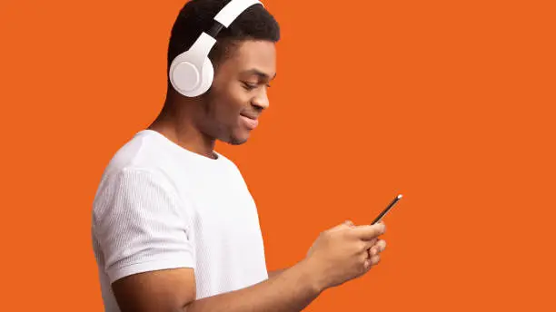 Photo of Side view of black man in wireless headphones