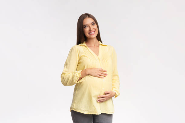 Pregnant woman holding baby clothes. Happy pregnant woman. Pregnancy, motherhood, people and expectation concept