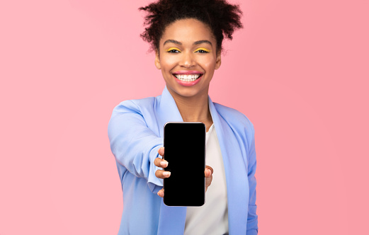 I Like This Cellphone. Millennial afro girl showing mobile phone with blank screen, pink background, copyspace, mock up