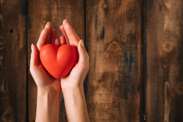istock Hand holding heart on wooden background 1201192812