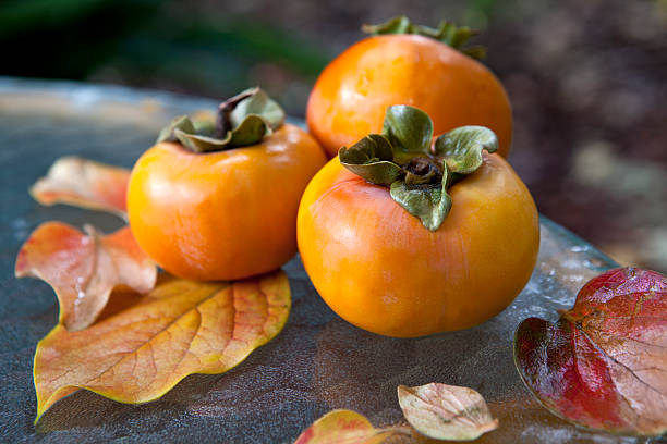 istock Persimmons with leaves on outdoor table - still life. 120119303