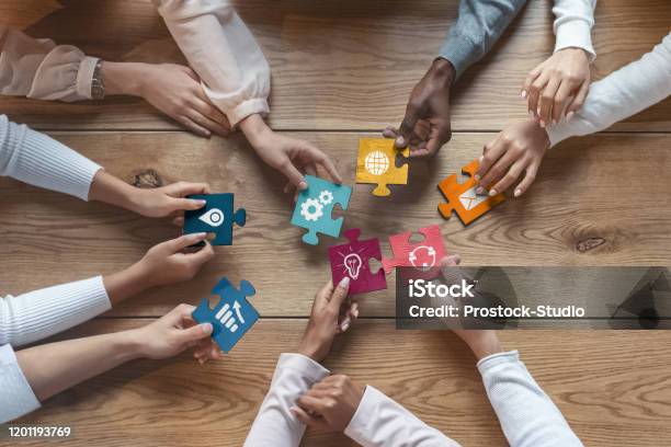 International Team Of Coworkers Putting Colorful Puzzles Together Stock Photo - Download Image Now
