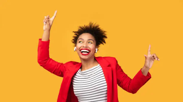 Photo of Smiling black girl listening to music points up