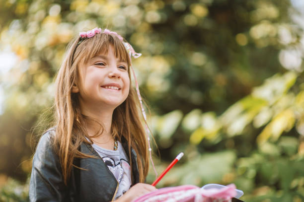 istock Pretty little girl outdoors excited about reading a book 1201195486