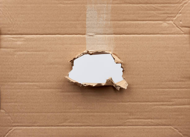 istock hole in brown cardboard paper with torn and curved edges 1201195554