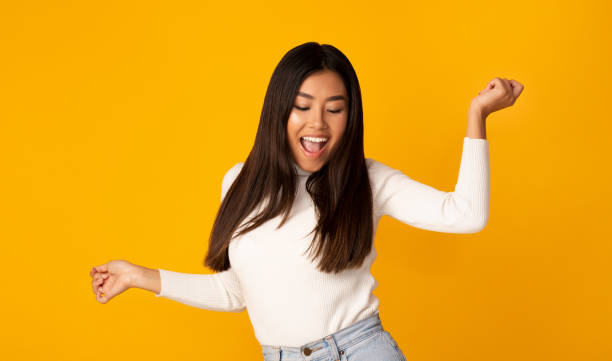 istock Playful asian girl dancing on yellow studio background 1201195657