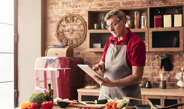 istock Grandfather reading recipe on tablet at kitchen 1201198442