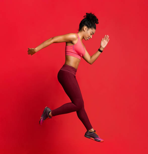 istock Sporty young woman exercising over red background 1201198672