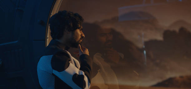 istock Male astronaut looking out of Mars base window 1201198705