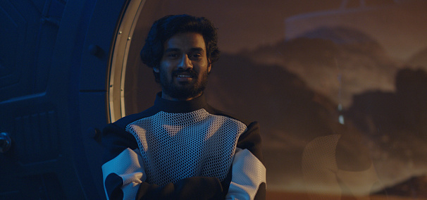 Medium shot of a male astronaut looking out of Mars base window