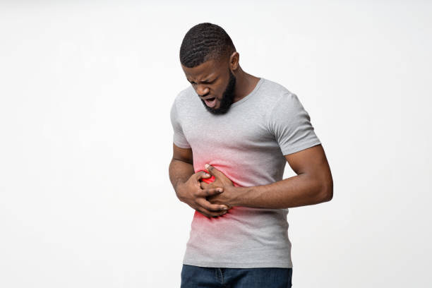 Young black guy suffering from stomach ulcer Young afro guy suffering from stomach ulcer, touching his tummy over white background, copy space human abdomen stock pictures, royalty-free photos & images