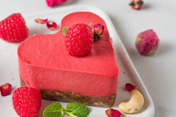 istock raw vegan raspberry heart shaped cake or cheesecake with fresh berries, nuts, mint and dried flowers. Valentines day dessert 1201200122