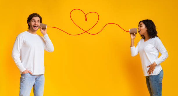 Affectionate afro girl singing love song to boyfriend through tin phone Love song. Affectionate afro girl sending romantic message to her boyfriend through tin phone, congratulating with Valentine's day, yellow background string telephone stock pictures, royalty-free photos & images