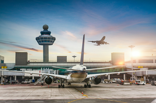 Near boarding gate bridge ground services are providing service to passenger planes prior to next takeoff in airport