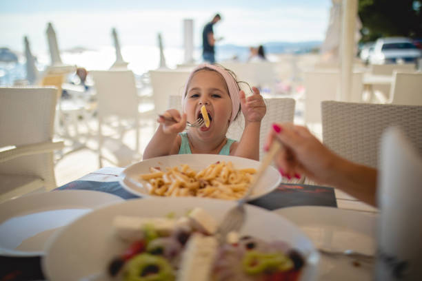 Little girl eating macaroni in a Greek beach restaurant