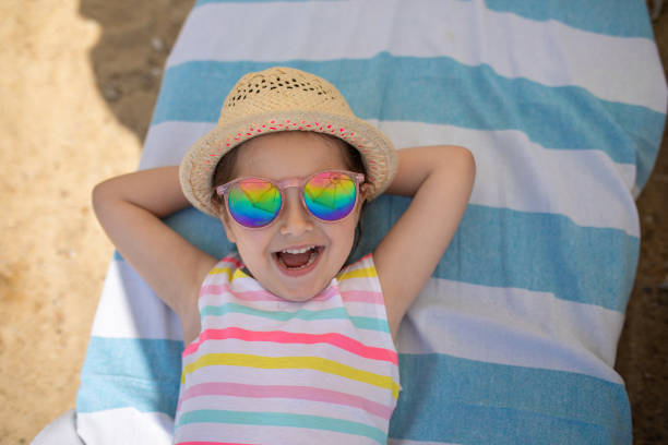 Little girl lying down on a beach towel and relaxing on the beach