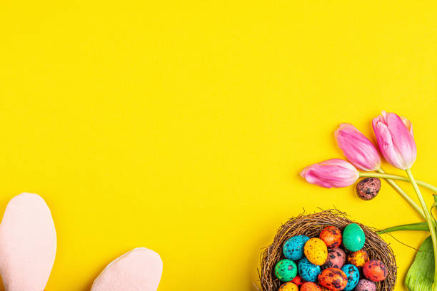 istock Stylish background with colorful easter eggs isolated on yellow background with pink tulip flowers. Flat lay, top view, mockup, overhead, template 1201202189