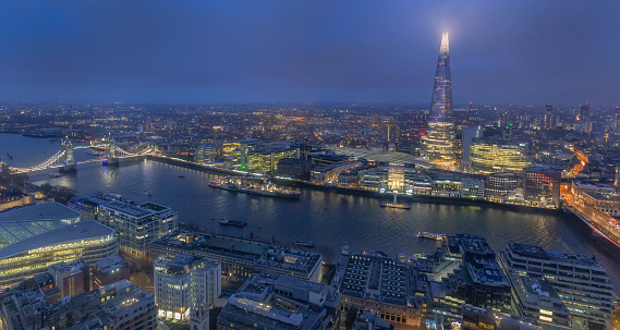 Night aerial view of Thames river, Tower Bridge and The Shard in London, England. Smog over city at autumn afternoon.