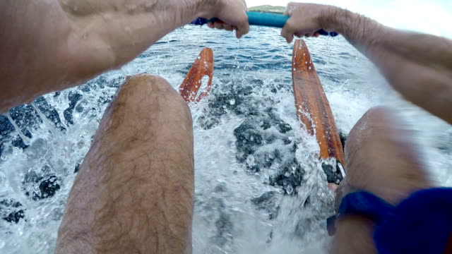 POV of a man successfully getting up on his vintage wooden water skis