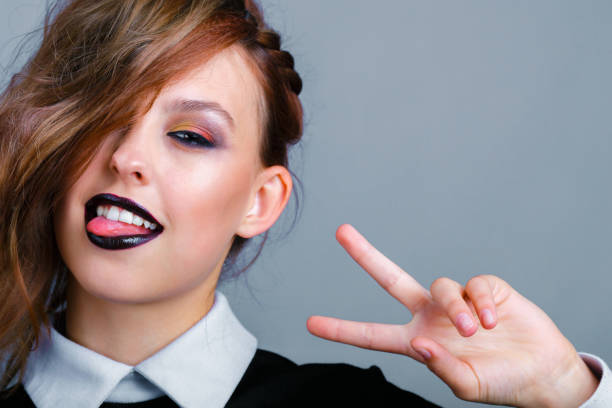 istock A young girl with bright makeup shows a victory sign 1201204326