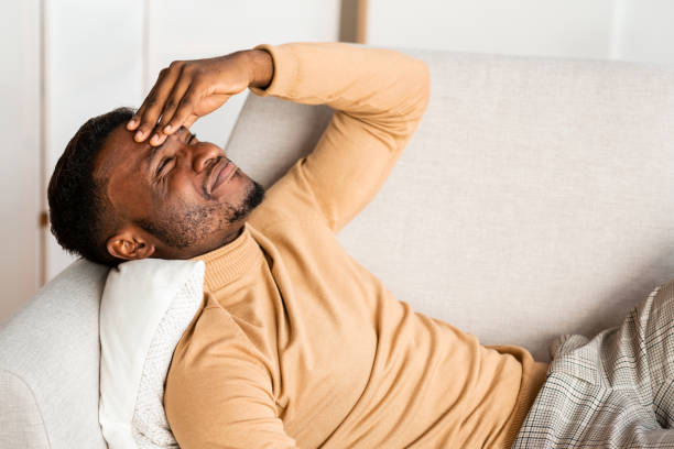 istock Man Having Headache Suffering From Pain Lying On Couch Indoor 1201204390