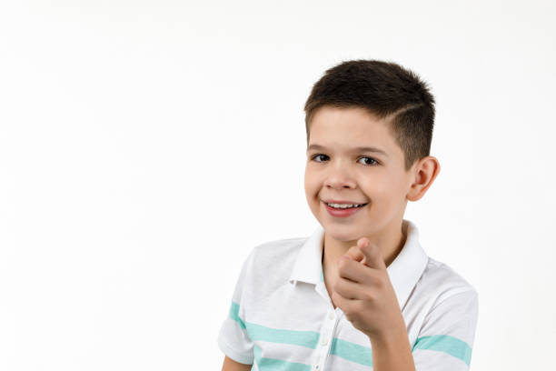 istock Cute smiling little boy in striped t-shirt pointing camera 1201204585