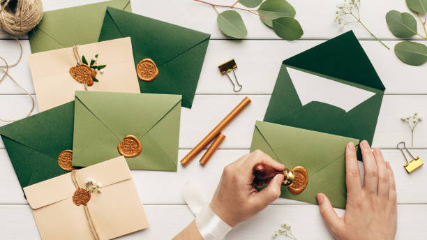 istock Female hands glue up envelopes with invitations on wedding 1201204860