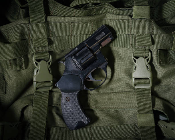 istock pistol revolver on a green army backpack 1201205102