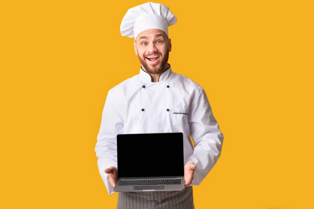 istock Chef Holding Laptop Computer Showing Blank Screen On Yellow Background 1201207952