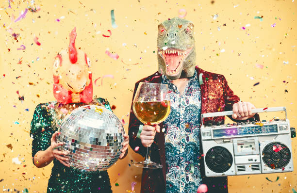 pareja loca celebrando la víspera de año nuevo con pollo y dinosaurio t-rex máscara - jóvenes gente de moda divirtiéndose bebiendo champán y escuchando música con boombox vintage - absurdo y vacaciones concepto - insólito fotografías e imágenes de stock