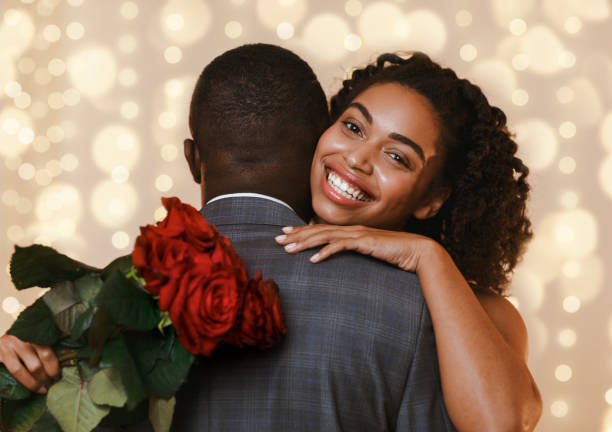 istock Happy black woman holding red roses while hugging her man 1201208299