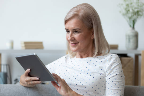 istock Mature woman busy using tablet at home 1201208515