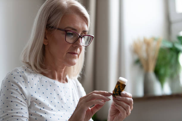 istock Senior woman reading medicines instruction on pills bottle 1201208554