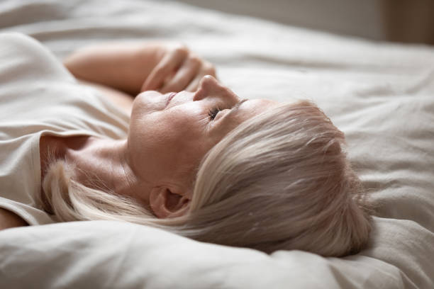 istock Tired mature woman relax sleeping in comfy bed 1201208596