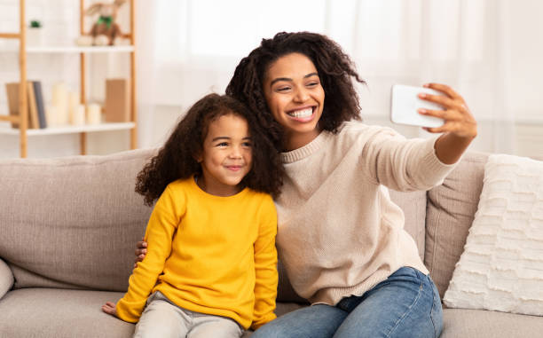 istock Happy Mother And Daughter Making Selfie Sitting On Sofa Indoor 1201209924
