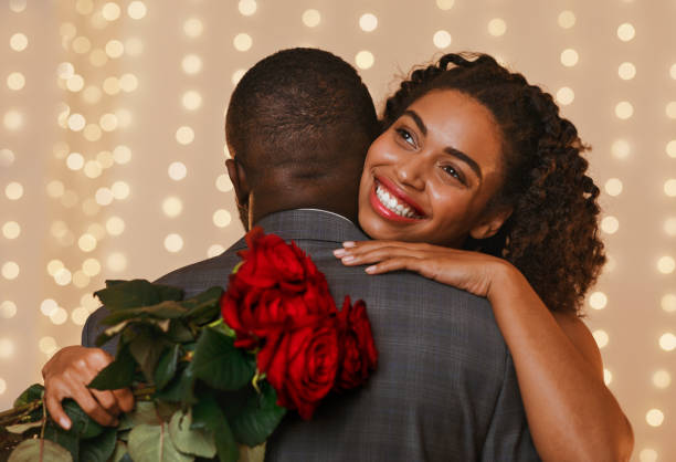 istock Attractive young woman holding red roses while hugging her man 1201210053