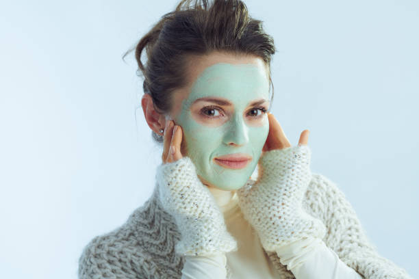 femme moderne de 40 ans avec le visage touchant vert de masque facial - human skin dry human face peeling photos et images de collection