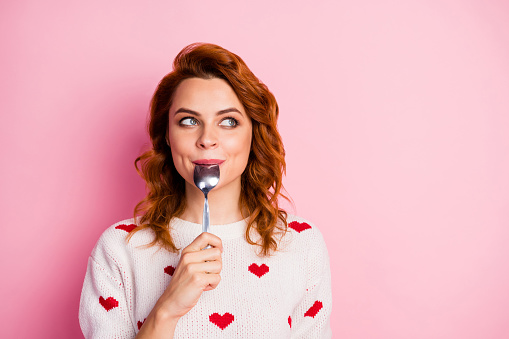 Close-up portrait of her she nice attractive pretty cute dreamy cheerful, wavy-haired girl licking spoon fantasizing creating recipe festal lunch breakfast isolated on pink pastel color background